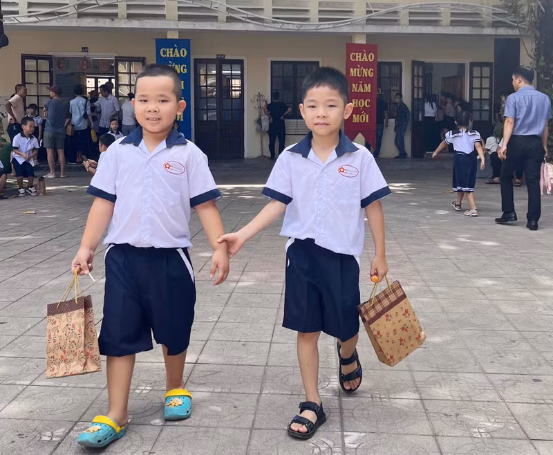 2 nam sinh chơi đùa cùng nhau trong khuôn viên trường xanh mát. Hình ảnh học sinh lớp 1 Thừa Thiên - Huế nô nức tựu trường sớm