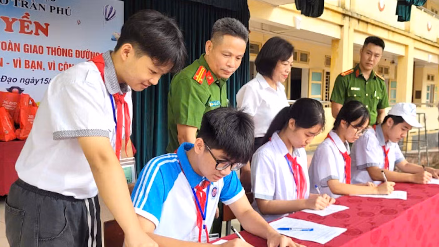 Học sinh Trường THCS Trần Phú (phường Trần Hưng Đạo) ký cam kết tại buổi ngoại khóa tuyên truyền pháp luật về bảo đảm trật tự, an toàn giao thông và kỹ năng sử dụng mạng xã hội an toàn.