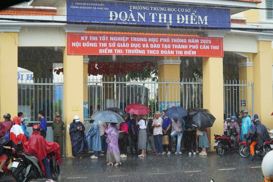 Phụ huynh đội áo mưa chờ con tại điểm thi Trường THCS Đoàn Thị Điểm, quận Ninh Kiều. Ảnh: Thành Thật. z6743120639030-89eba7bca0f4d7433625ad8ddf55a1c4.jpg