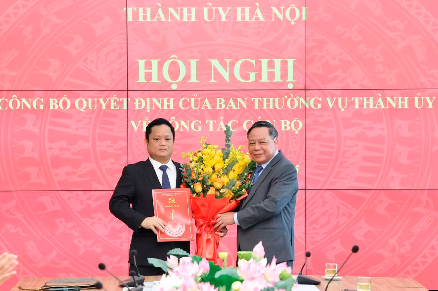 Phó Bí thư Thường trực Thành ủy Hà Nội Nguyễn Văn Phong trao quyết định và tặng hoa chúc mừng ông Vũ Minh Tuấn. Ảnh: Q.T