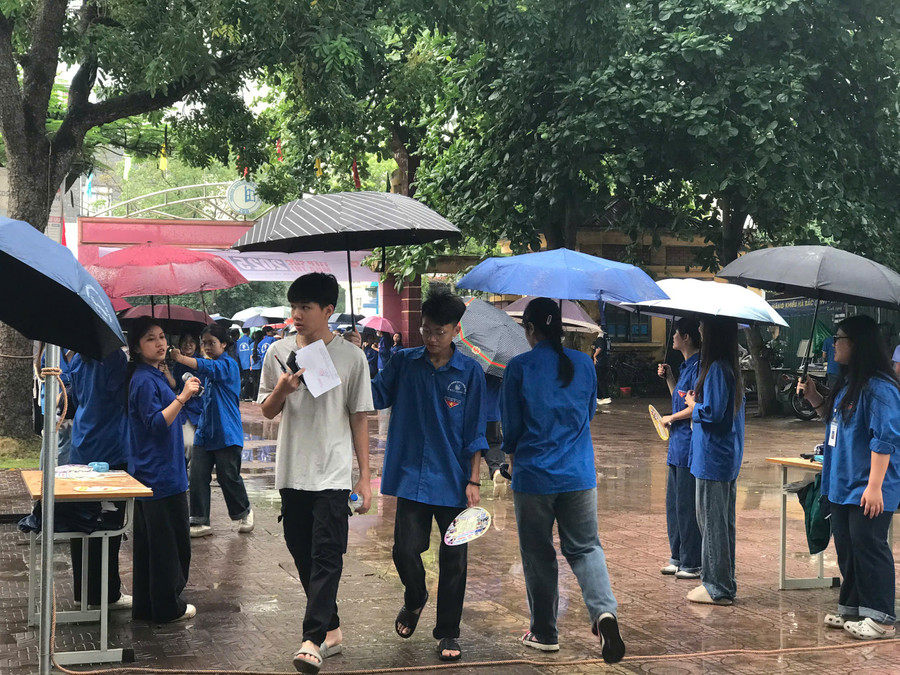 Thanh niên tình nguyện "đội mưa" hỗ trợ thí sinh vào khu vực phòng thi. z6673019435244-b51c4d2b080c191ece00424ceb8c6b32.jpg