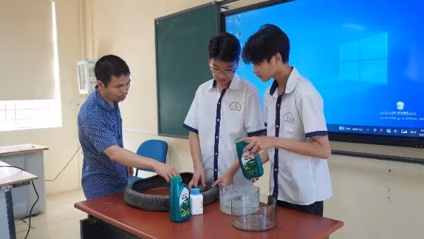 Thầy giáo Dương Quốc Trọng (bên trái) hướng dẫn học trò thực hiện dự án khoa học kỹ thuật. 