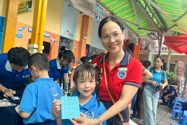 Bé Gia Hân, học sinh lớp 2/6, Trường tiểu học Đinh Tiên Hoàng khoe cô giáo những trạm vui chơi mà em đã thực hiện được trong ngày hội. Ảnh: MD