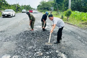 Ông Lê Bá Toàn (áo sơ mi) cùng lực lượng dân quân trong khu vực vá đường Nguyễn Văn Cừ.