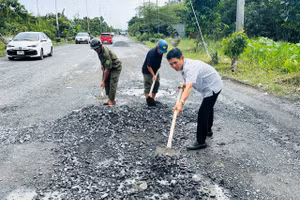 Ông Lê Bá Toàn (áo sơ mi) cùng lực lượng dân quân trong khu vực vá đường Nguyễn Văn Cừ.
