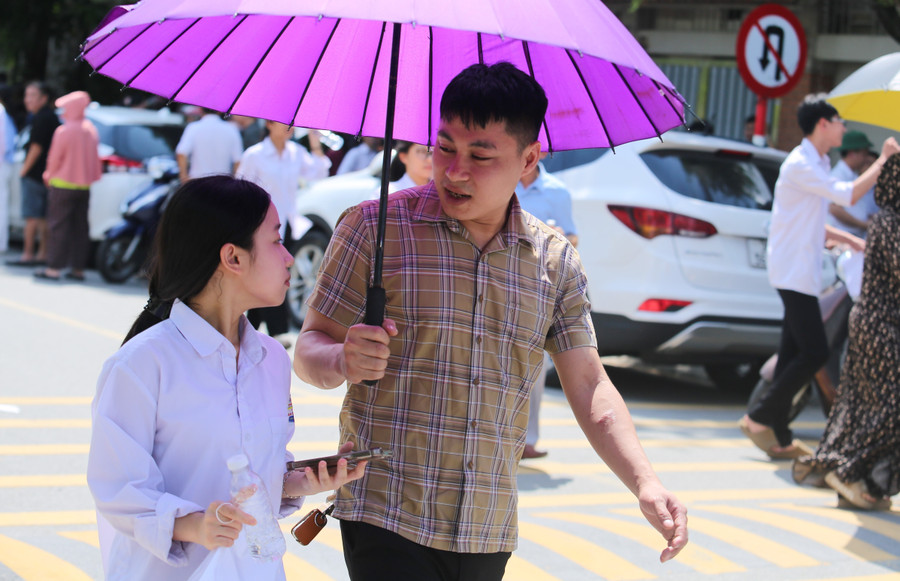 Người bố vừa che nắng vừa ân cần hỏi con gái về bài thi sáng nay. 23.jpg
