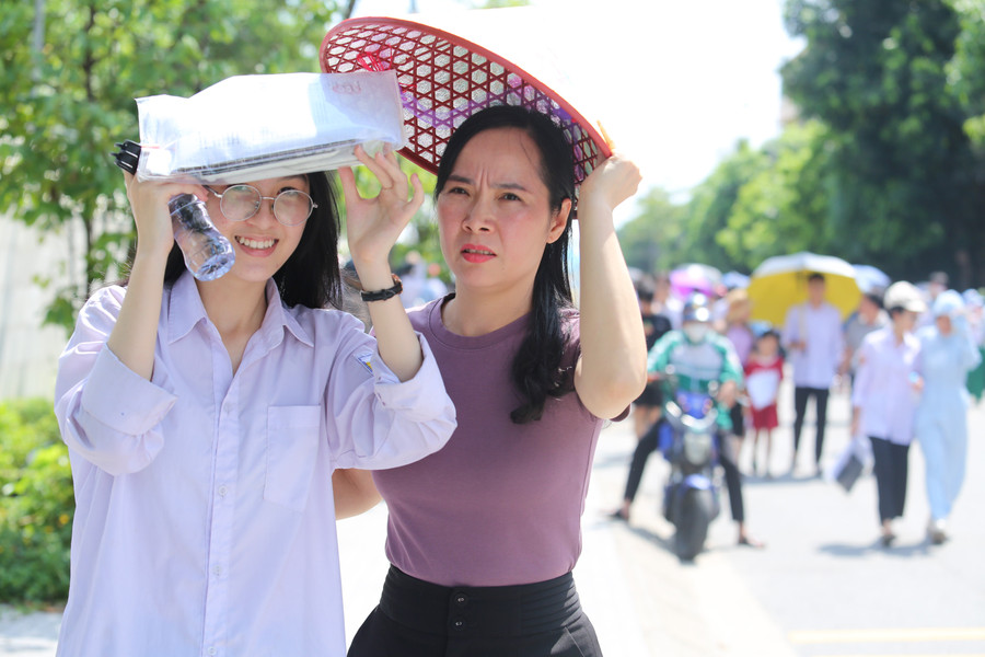 Phụ huynh che nắng cho các sĩ tử sau khi rời điểm thi. 22.jpg
