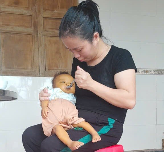 Tranh thủ khi bé Phong hết cơn đau, chị Hường cố đút cho con từng thìa cháo loãng. img-20250924-200204.jpg