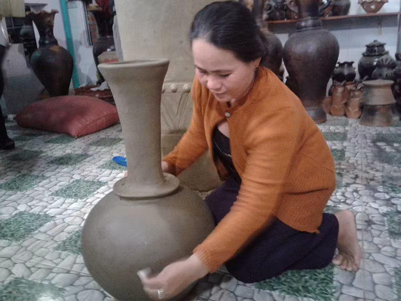 Một nữ nghệ nhân đang tạo dáng một chiếc bình gốm