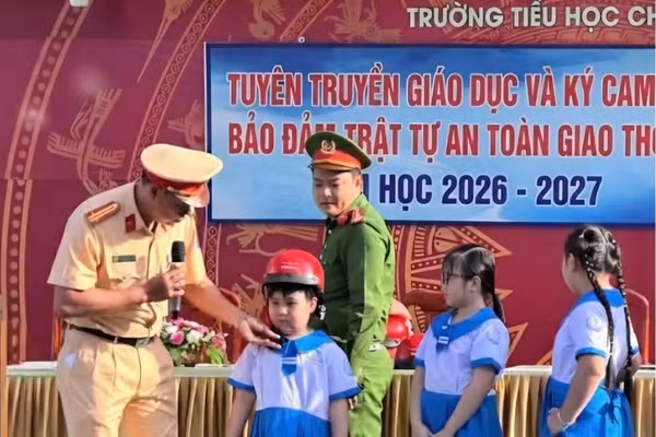 Cán bộ Phòng CSGT, Công an tỉnh An Giang hướng dẫn học sinh đội mũ bảo hiểm đúng quy định.