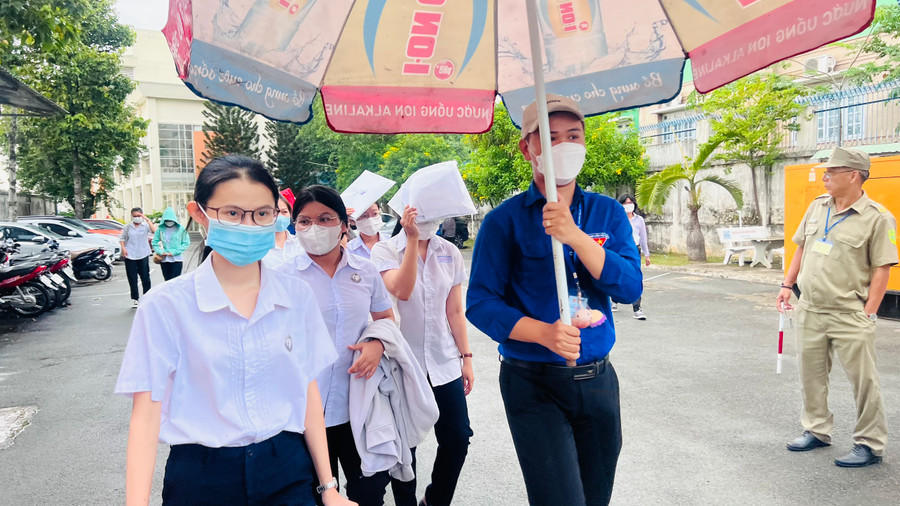 Các thí sinh được các tình nguyện viên che dù từ phòng thi ra cổng. Các thí sinh được các tình nguyện viên che dù từ phòng thi ra cổng.