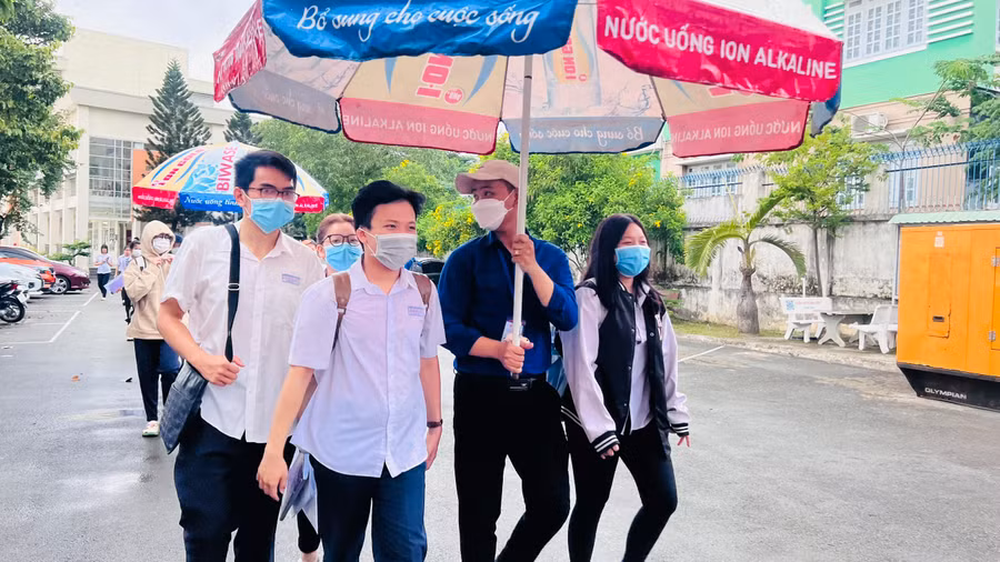 Các thí sinh được tình nguyện viên hỗ trợ ra về khi trời mưa lớn.