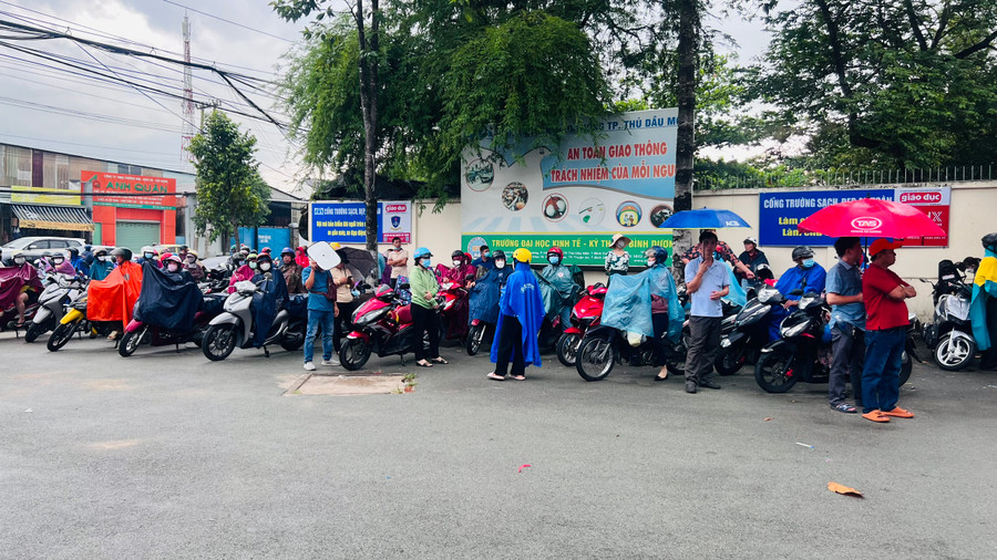 Phụ huynh cũng &quot;đội mưa&quot; chờ con em mình ra về.