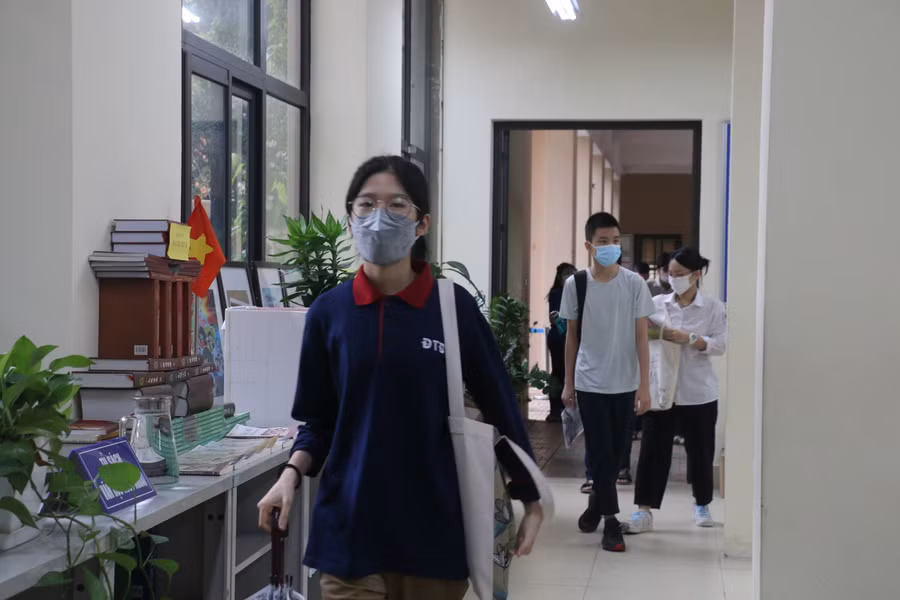 Sau khi đo thân nhiệt, thí sinh xếp hàng lên phòng thi.