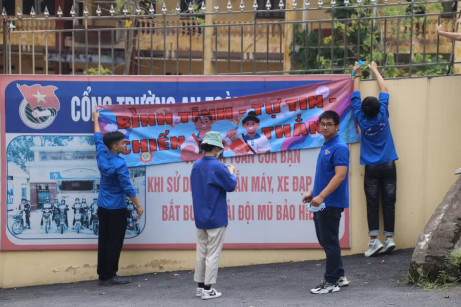 Lực lượng thanh niên tình nguyện treo băng rôn cổ vũ thí sinh tại điểm thi Trường THPT Văn Giang.