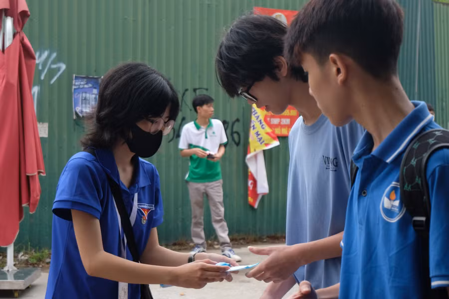 Tình nguyện viên tại điểm thi Trường THPT Trung Văn phát khẩu trang miễn phí cho thí sinh.