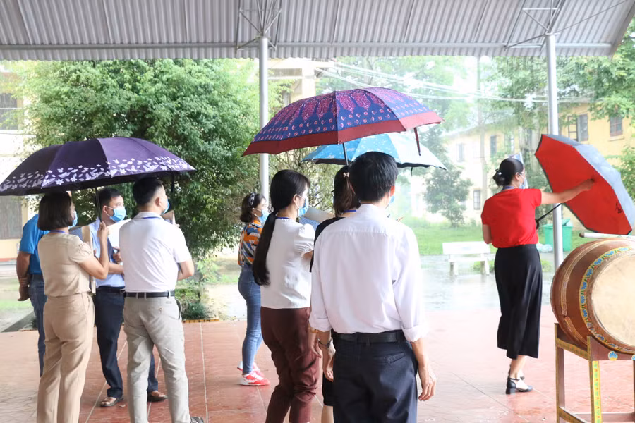 Cán bộ coi thi chuẩn bị ô đón thí sinh vào điểm thi.