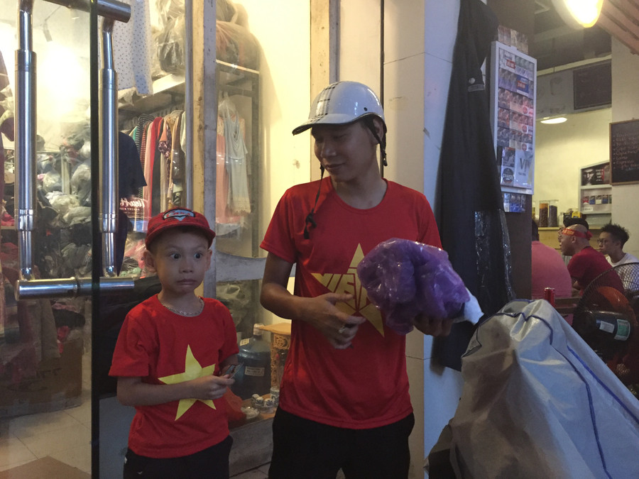 Hai bố con vào cửa hàng mua áo đỏ sao vàng và nhanh chóng thay trang phục mới