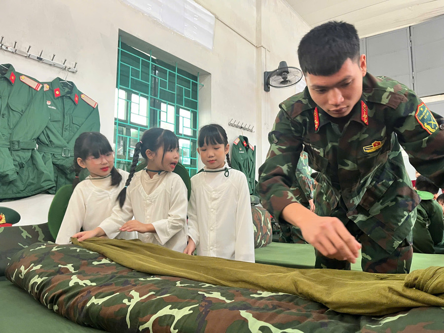 Chiến sĩ ở Đại đội Phòng hóa 66, Lữ đoàn 86 hướng dẫn học sinh gấp chăn màn. tay-tuu-3.jpg