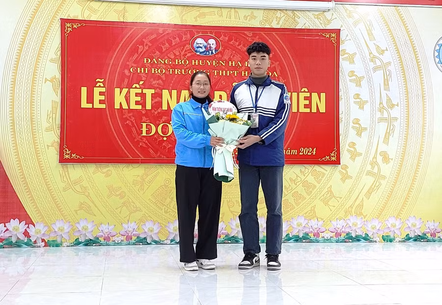 Bí thư Đoàn trường Đàm Phương Anh tặng hoa chúc mừng đảng viên Quàng Tiến Đạt.