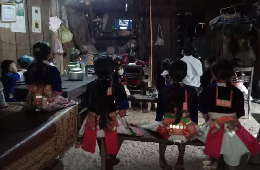 Ở trong gian nhà công cụ của thầy cô ở bản Phá Kháo, xã Mai Sơn, những đứa trẻ người Mông mặc trang phục truyền thống, xem lễ khai giảng qua chiếc tivi nhỏ của thầy cô, chạy bằng nguồn điện tua-bin tự chế.