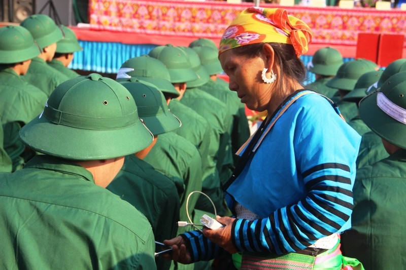 Một bà mẹ (người Mông) đưa điện thoại di động cho con trai của mình trước khi nhập ngũ.