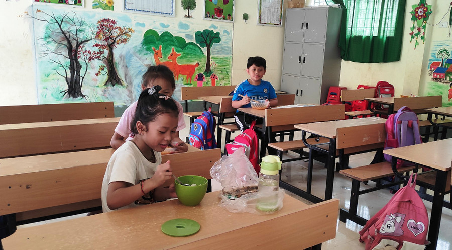 Một số học sinh ăn cơm trưa tại lớp để buổi chiều tiếp tục học. Ảnh: Thế Lượng.