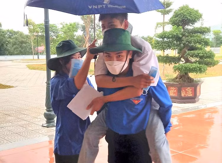 Thí sinh bị đau chân được tình nguyện viên hỗ trợ tại điểm thi TrườngTHPT Tân Sơn