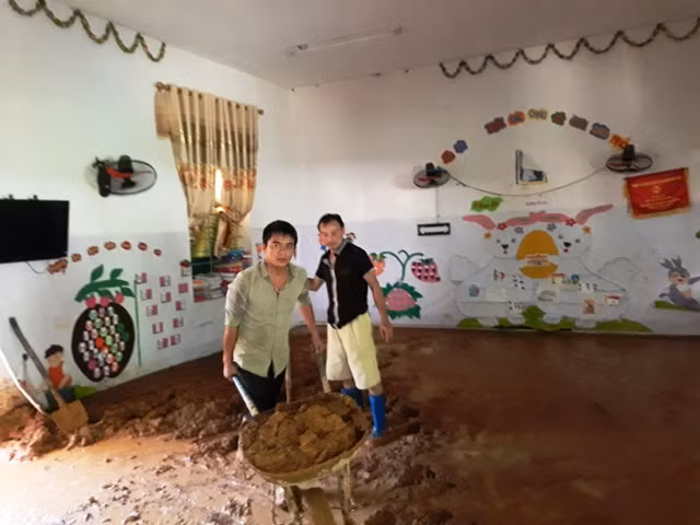 Các thầy giáo dọn dẹp bùn đất trong lớp học ở Trường Mầm non Na Mèo.