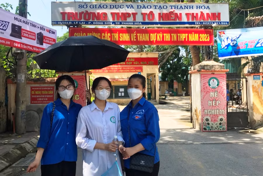 Em Hoàng Thị Hằng (áo trắng) tranh thủ chụp hình với thanh niên tình nguyện tại cổng trường trước khi vào phòng thi. Ảnh: Lường Toán.