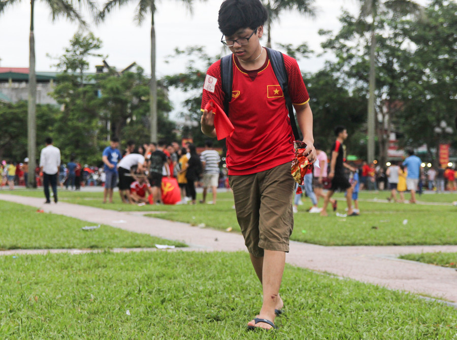 Một cậu bé nhặt băng rôn, hình ảnh cổ vũ bị vứt lại sau trận đấu