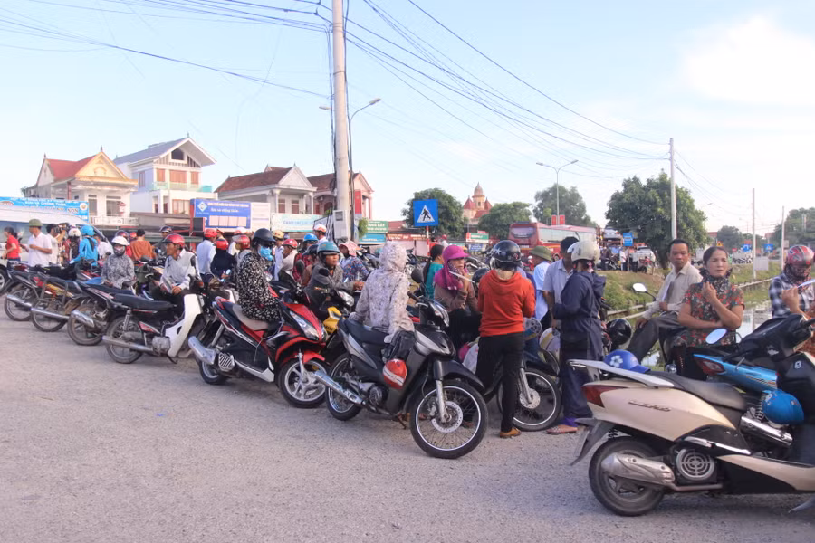 Phụ huynh dựng xe ở bên lề đường đứng đợi con.