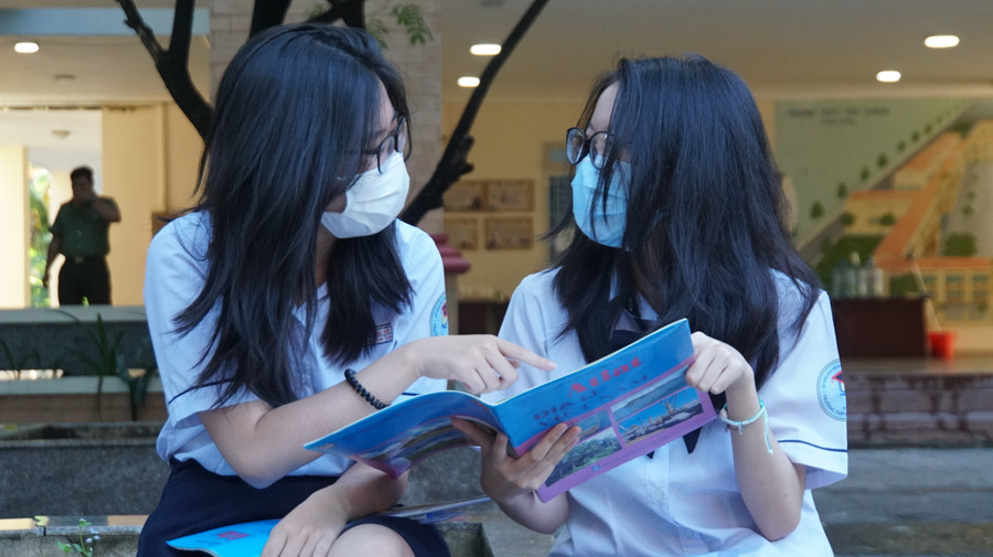 Hai nữ sinh chọn bài thi Khoa học xã hội tranh thủ trao đổi bài trước giờ vào phòng thi. Ảnh: Mạnh Tùng