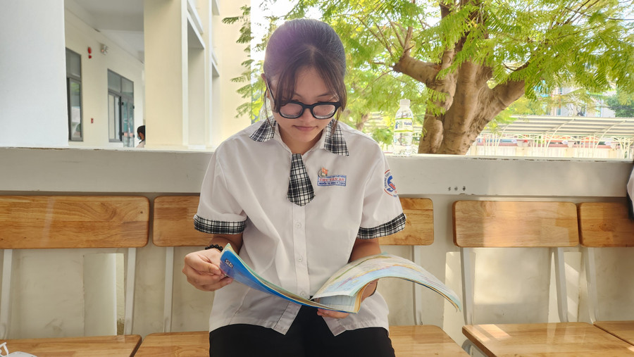 Nữ sinh tranh thủ ôn bài môn Địa lý trước giờ vào phòng thi. Ảnh: Đức Anh