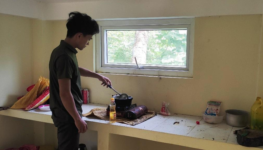 Em Giàng A Ku - học sinh lớp 12D, đang tự nấu ăn trong bếp của ngôi nhà vừa được sửa sang.