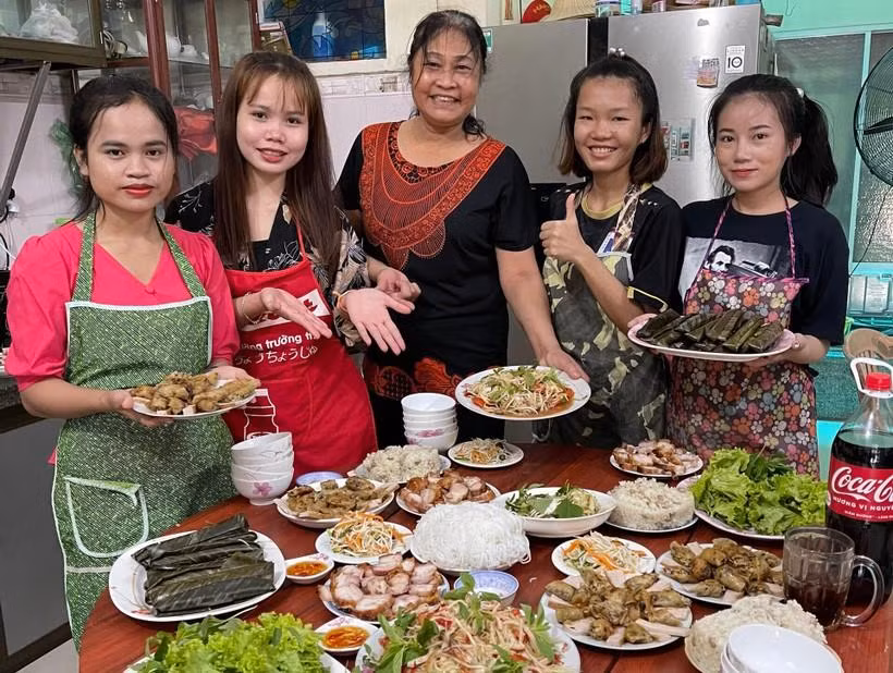 Các bạn sinh viên Lào được “mẹ đỡ đầu” Trần Thị Nguyện dẫn về nhà dạy nấu món ăn Việt Nam.
