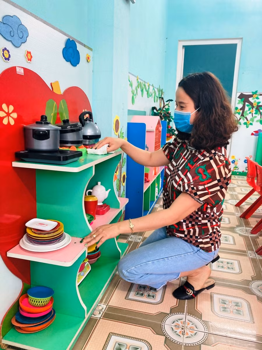 Giáo viên làm vệ sinh đồ dùng cho học sinh trong lớp học.