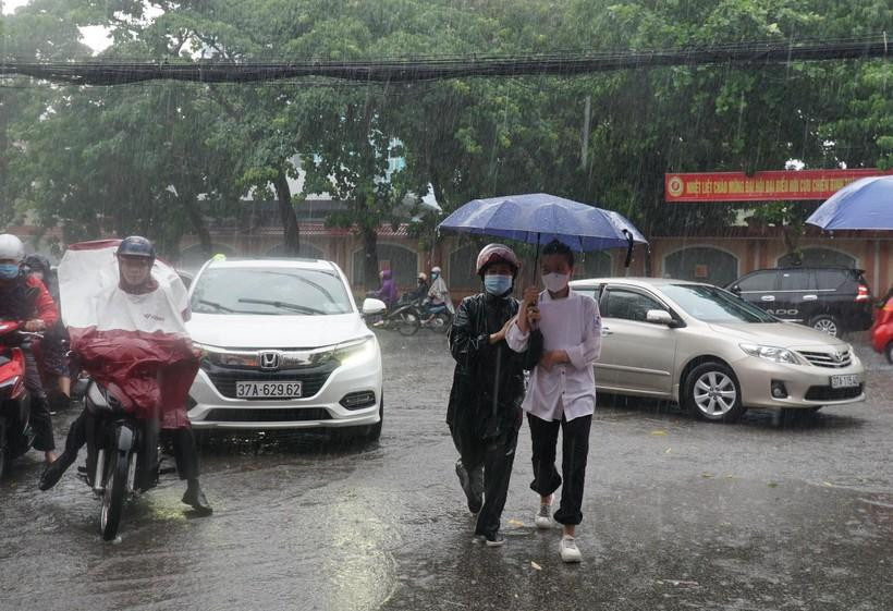 Thí sinh và phụ huynh đội mưa đến điểm thi tại Trường THPT Huỳnh Thúc Kháng, TP Vinh, Nghệ An.