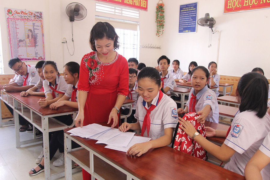 Cô giáo chủ nhiệm trao đổi với học sinh và ghi báo cáo tình hình đầu năm của lớp