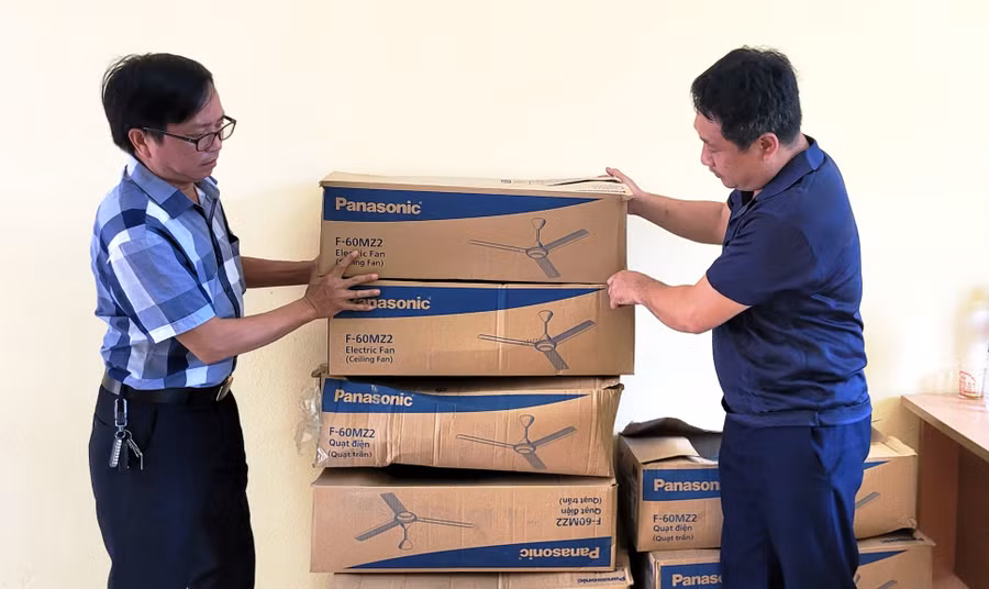 Thầy giáo Trương Đức Văn - Hiệu trưởng Trường THCS Trung Sơn (phải) đón nhận quạt trần do Trường Mầm non Trường Thi B, TP Thanh Hóa gửi tặng. Ảnh: HĐ