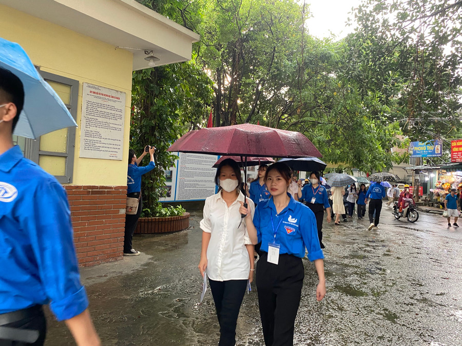 Các bạn tình nguyện viên che ô cho các sĩ tử vào thi khi trời mưa.