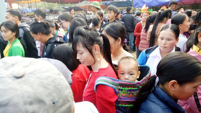 Mẹ địu con xuỗng chợ giữ dòng người ken đặc.