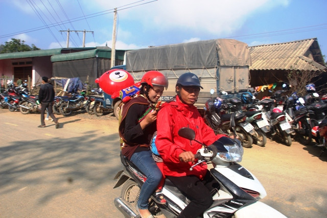 Một cặp vợ chồng, con cái đến chợ bằng xe máy.