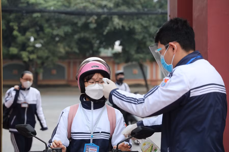 Trường THPT Huỳnh Thúc Kháng phân công học sinh trong ban nề nếp đo thân nhiệt cho các bạn trước khi vào trường.