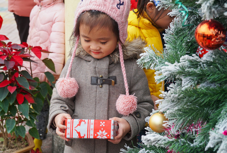 Bạn nhỏ thích thú với gói quà bọc giấy có hình chú tuần lộc