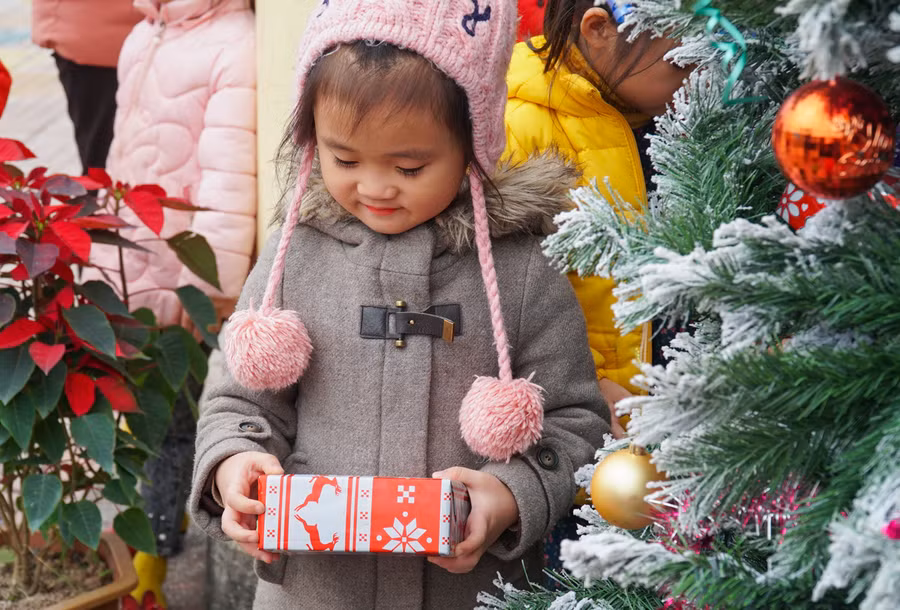 Bạn nhỏ thích thú với gói quà bọc giấy có hình chú tuần lộc