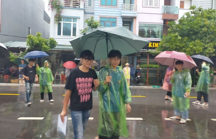 Các tình nguyện viên tiếp sức mùa thi nhiệt tình che ô đón thí sinh vào Hội đồng coi thi Trường THPT Công Nghiệp Việt Trì.