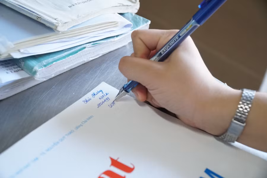 Các bạn thí sinh tại điểm thi Trường phổ thông DTNT THPT tỉnh Nghệ An ghi tên, số báo danh của mình vào Atlat Địa lý để giám thị kiểm tra trước khi vào phòng thi. Ảnh: Hồ Lài.