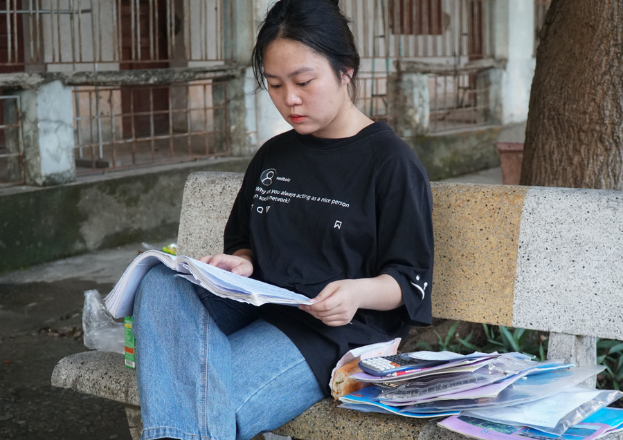 Thí sinh Ngô Thị Thơm tranh thủ đọc lại lý thuyết trước giờ vào thi môn Tổ hợp Khoa học xã hội. Ảnh: Hồ Lài.