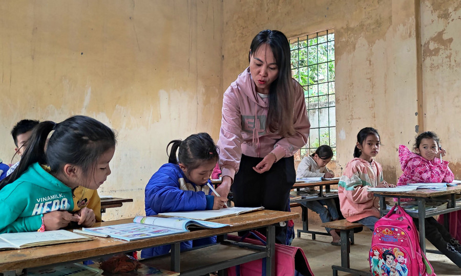 Cô giáo ở điểm trường Tân Sơn đang nắn nót chỉ cho học trò của mình từng nét chữ. Ảnh:TL.